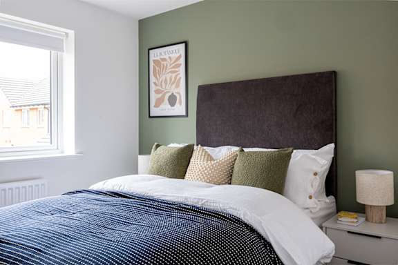 A bedroom with a large bed and a picture on the wall.