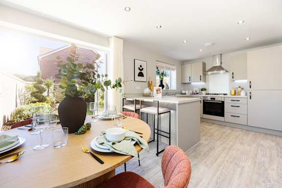 A modern kitchen with a dining table set for two.