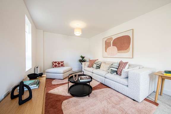 A living room with a white couch, a coffee table, and a rug.