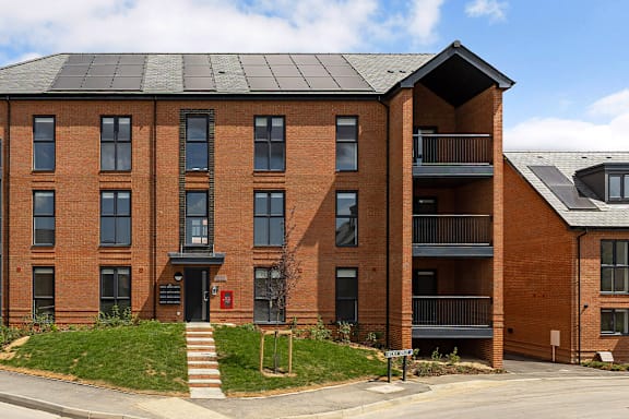 A red brick building with a black roof and a balcony on the second floor.
