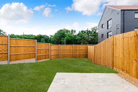 A backyard with a wooden fence and a green lawn.