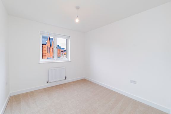 A white room with a window and a radiator on the floor.