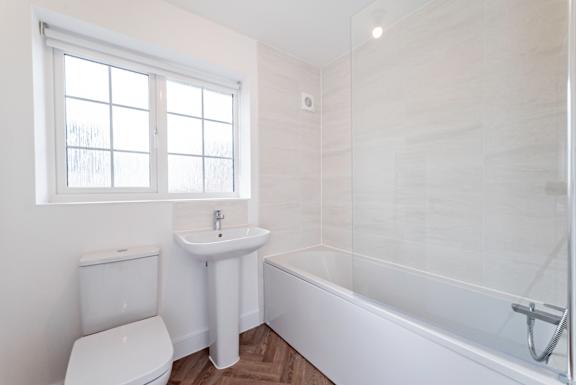 A white bathroom with a toilet, sink, and bathtub.