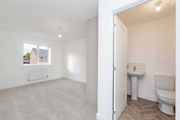 A white bathroom with a toilet, sink, and window.