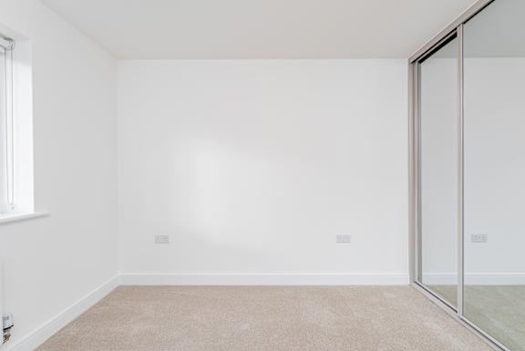 A room with a carpeted floor and a sliding glass door.