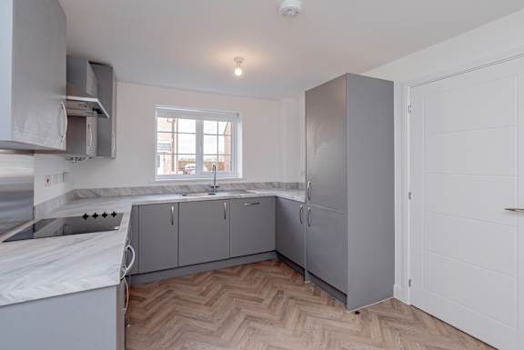 A kitchen with a white counter top and grey cabinets.
