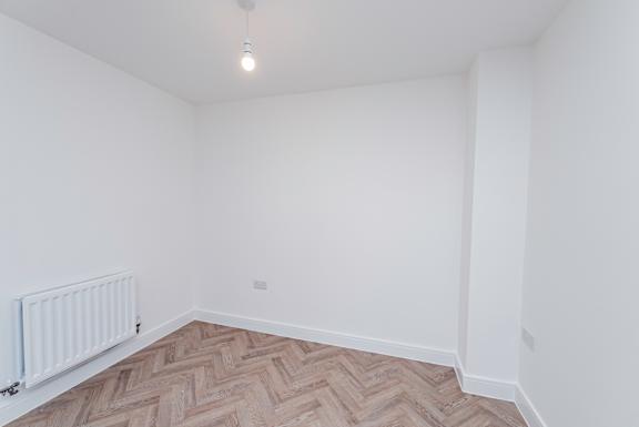 A room with a white wall and a radiator on the floor.