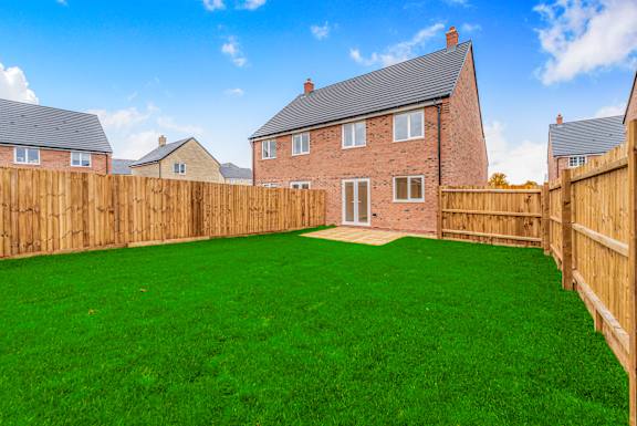 A backyard with a wooden fence and a house in the background.