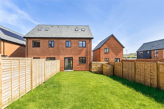 A house with a wooden fence and green lawn.