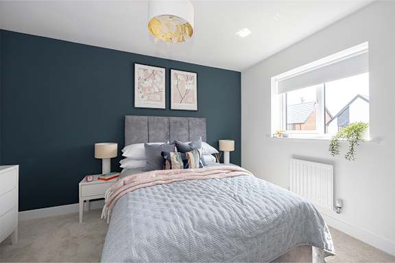 A bedroom with a bed, nightstand, and a window.