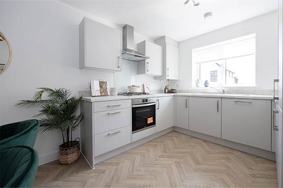 A modern kitchen with a green chair and a plant.