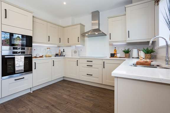 A kitchen with white cabinets and a black fridge.