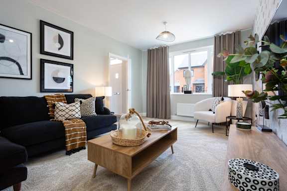 A living room with a black couch, a wooden coffee table, and a white chair.