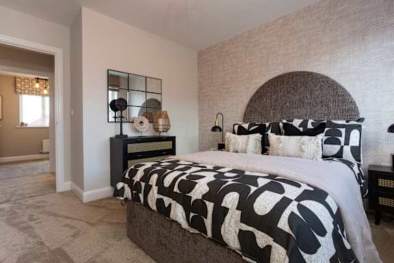 A bedroom with a large bed and a nightstand with a clock.