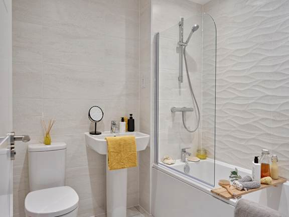 A white bathroom with a toilet, sink, and shower.