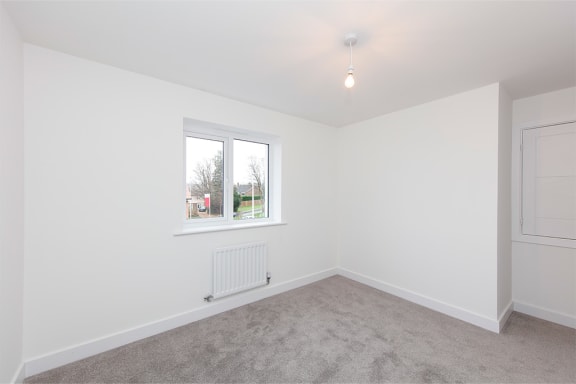 a bedroom with white walls and a window