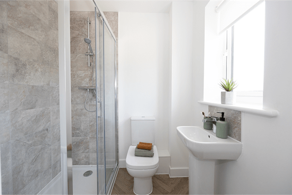 A bathroom with a toilet, sink, and shower.