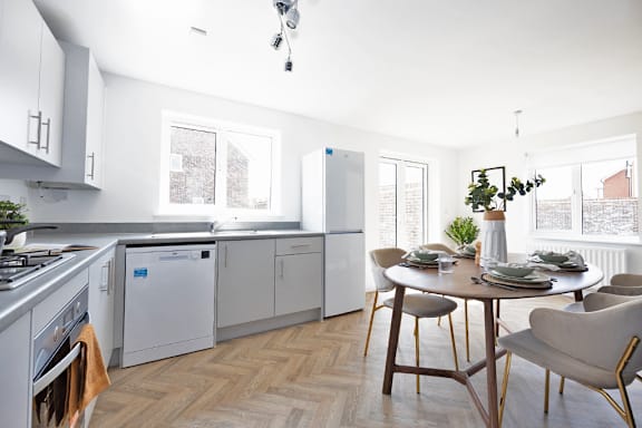 A modern kitchen with a dining table set for two.