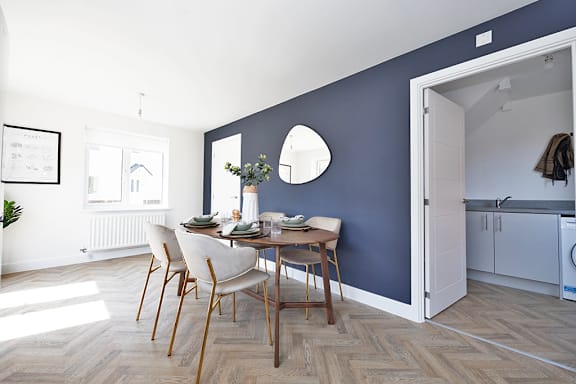 A dining room with a table set for two and a view of a kitchen.