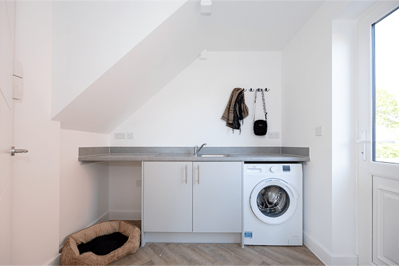 A laundry room with a washing machine and a dog bed.