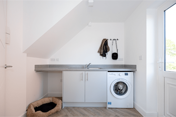 A laundry room with a washing machine and a dog bed.