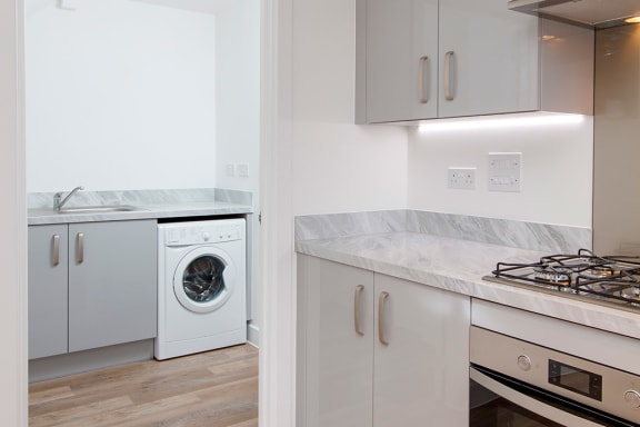 a kitchen with white cabinets and a washing machine in it