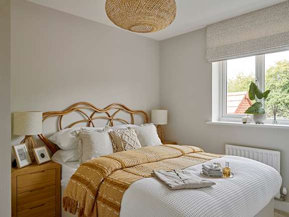 A bedroom with a bed, nightstand, and window.