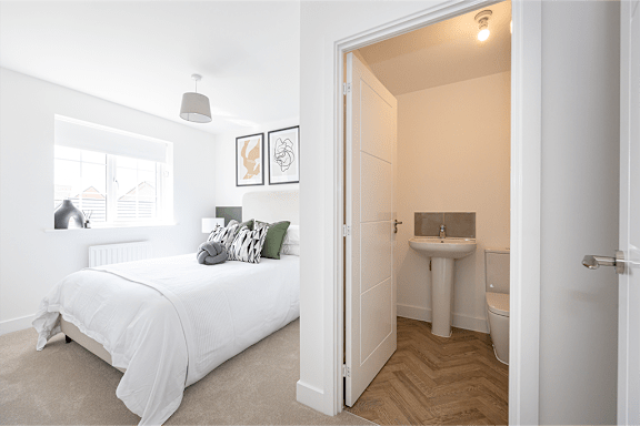 A white bedroom with a bed, sink, and toilet.