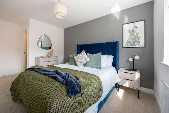 A bedroom with a bed, nightstand, and a mirror on the wall.