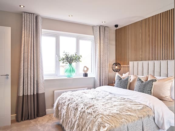 A bedroom with a large bed and a window with curtains.