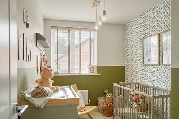a nursery with green and white wallpaper and a crib and a teddy bear