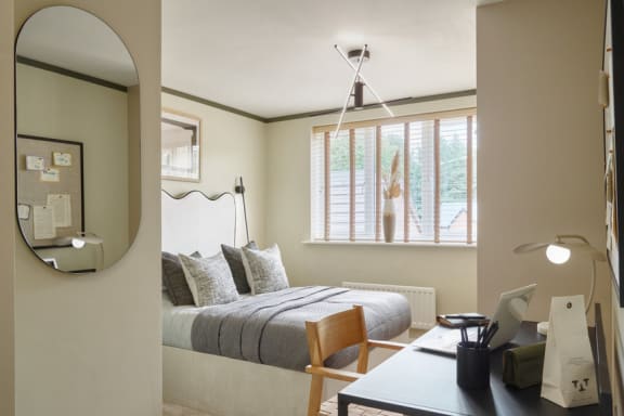 a bedroom with a bed and a desk and a mirror