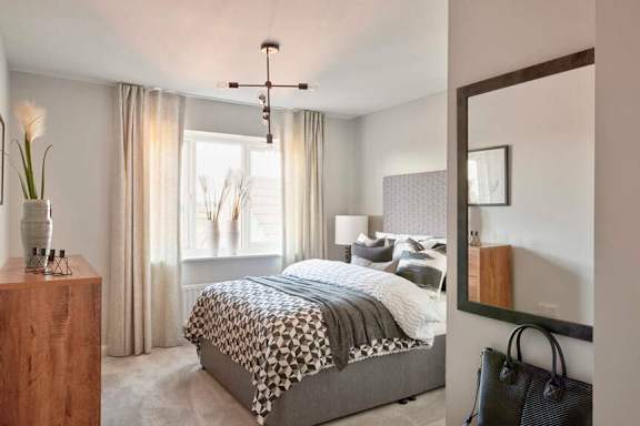 A bedroom with a bed, a dresser, a mirror, and a vase with a flower on top of it.