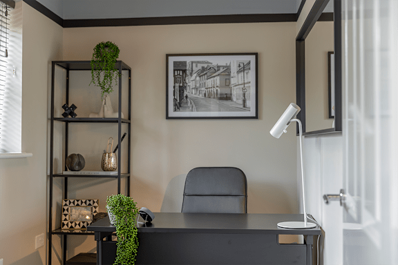 A black and white photo hangs on a wall above a black desk.