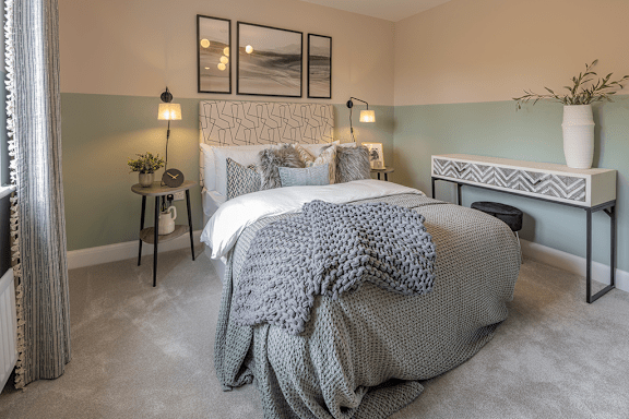 A bedroom with a large bed and a grey blanket.