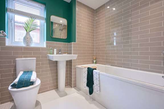 A white toilet sits next to a white sink in a bathroom with green walls.