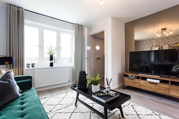 A living room with a green sofa, a black coffee table, and a flat screen TV.