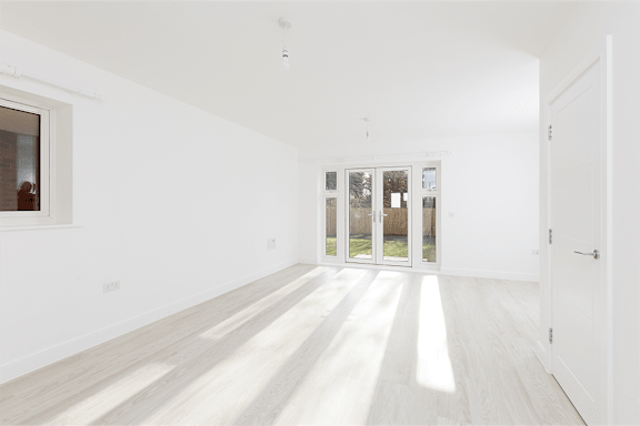 A white room with wooden floors and a door leading outside.