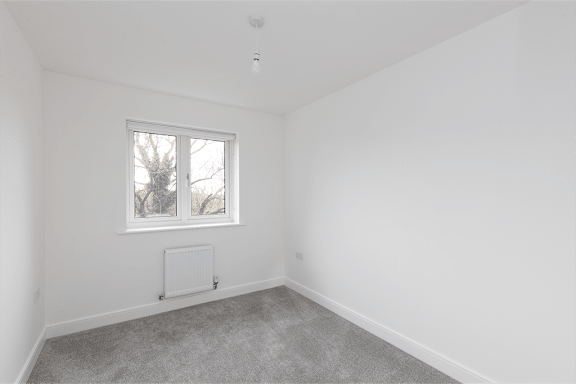 A room with a window and a radiator on the floor.