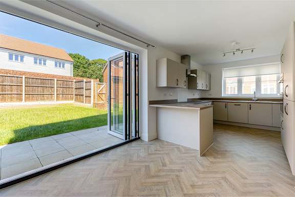 A kitchen with a white countertop and wooden flooring.