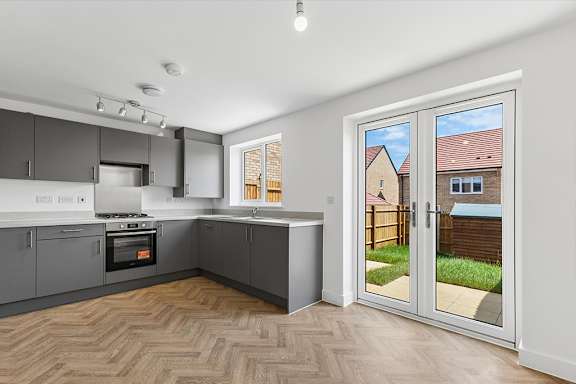 A kitchen with a wood floor and a window overlooking a backyard.