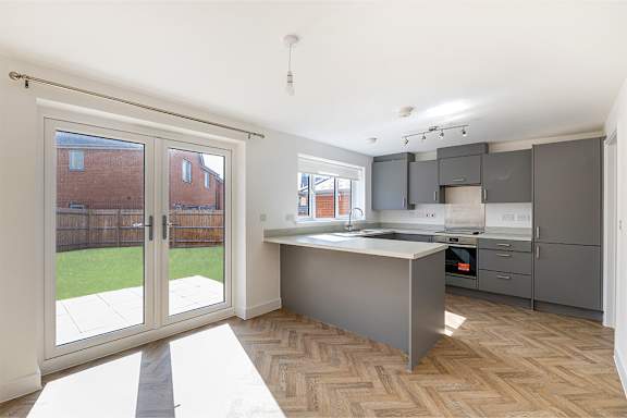 A kitchen with a large island and a view of a backyard through the sliding glass doors.