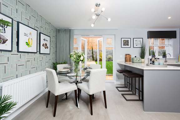 A dining room with a table set for two and a kitchen area in the background.