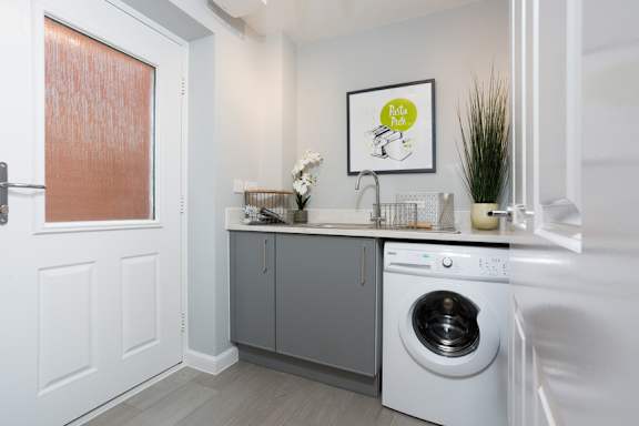 A laundry room with a washing machine and a framed picture on the wall.