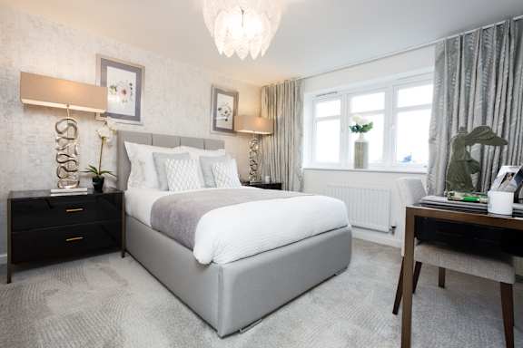 A bedroom with a large bed, a desk, and a chair.