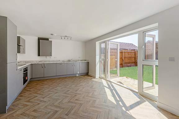 A kitchen with a marble counter top and a wooden floor.