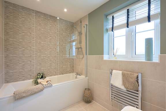 A bathroom with a white tub and a window with blinds.