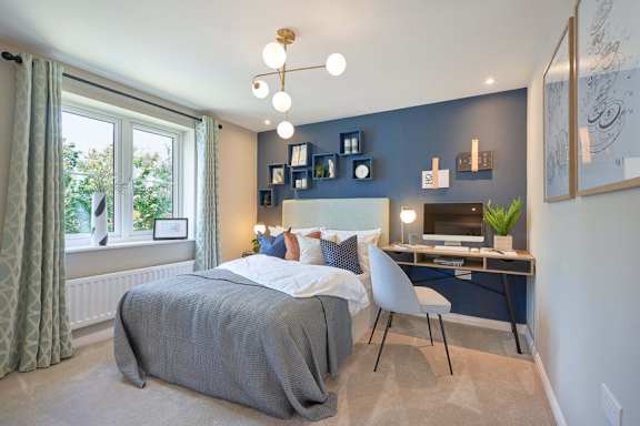A bedroom with a bed, desk, and chair.