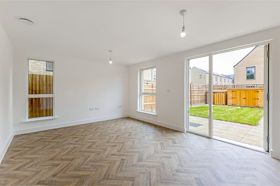 A room with a herringbone patterned floor and a sliding glass door.