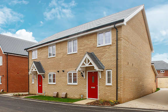 A brick house with a red door and white windows.